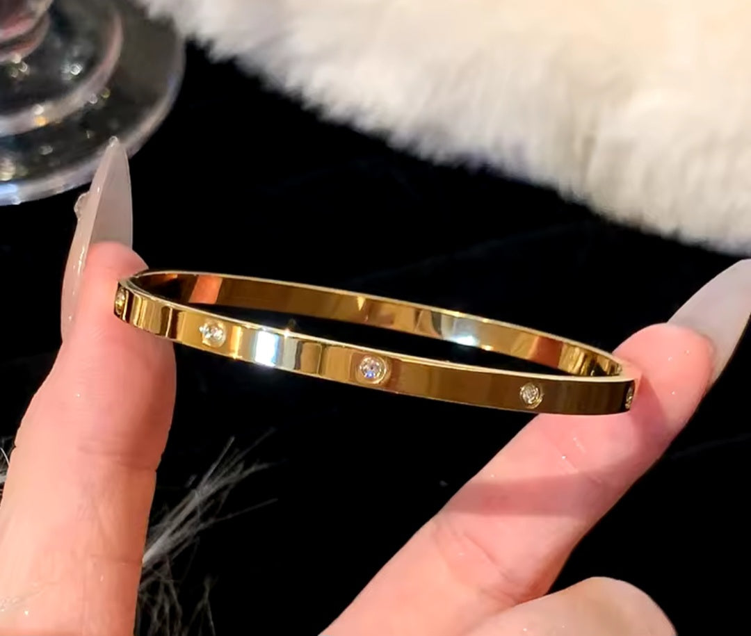 Pulsera de acero inoxidable chapada de oro con incrustaciones de circon/ Gold-plated stainless steel bracelet with zircon inlay.