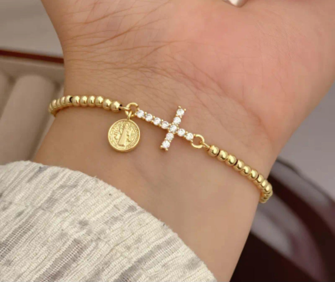 Pulsera ajustable dorada con dije de cruz con circones y medalla religiosa/ Adjustable Gold Bracelet with Cross Charm, Cubic Zirconia, and Religious Medal.