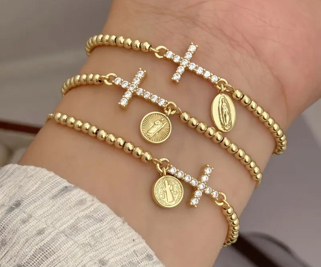 Pulsera ajustable dorada con dije de cruz con circones y medalla religiosa/ Adjustable Gold Bracelet with Cross Charm, Cubic Zirconia, and Religious Medal.